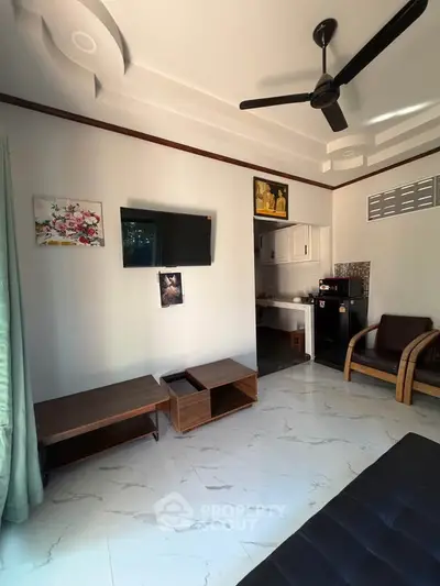 Modern living room with sleek furniture and wall-mounted TV, featuring a ceiling fan and stylish decor.