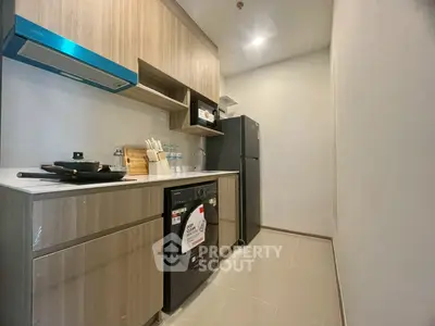 Modern kitchen with sleek appliances and wooden cabinetry in a compact layout.