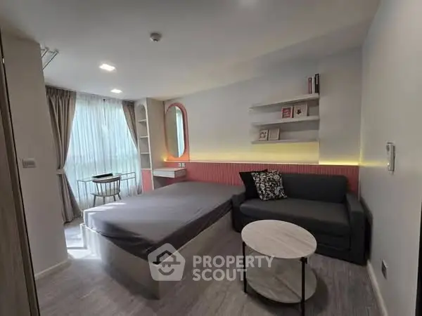 Modern bedroom with stylish decor and natural light, featuring a cozy sofa and elegant shelving.