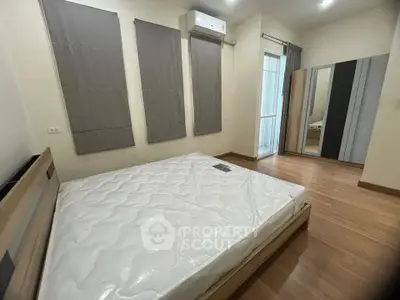 Modern bedroom with wooden flooring and large windows in a stylish apartment.