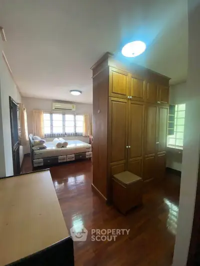 Spacious bedroom with wooden flooring and ample natural light.