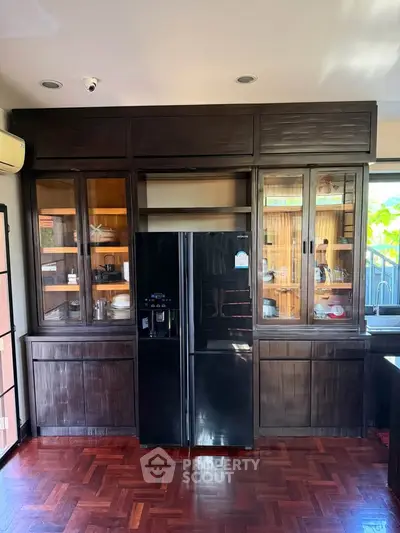 Spacious kitchen with dark wood cabinetry and modern appliances, featuring a sleek black refrigerator.
