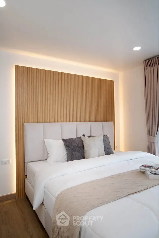 Modern bedroom with stylish headboard and cozy bedding in a well-lit interior.