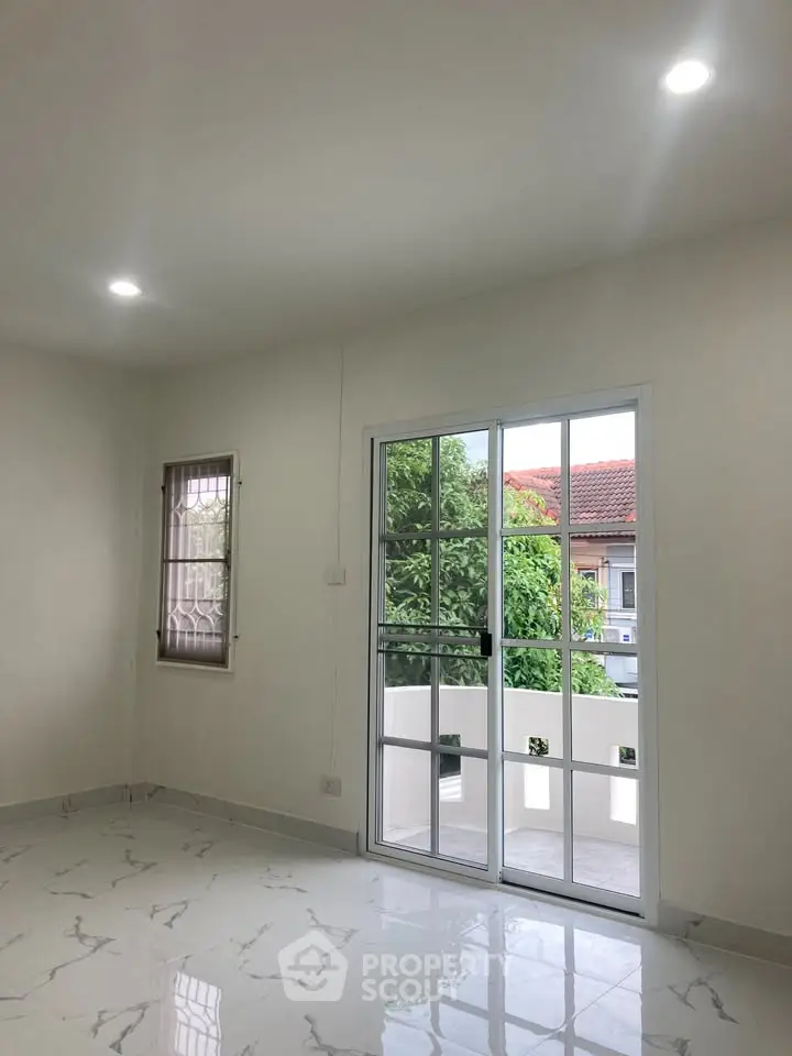 Bright living room with marble floor and glass doors leading to a small balcony.