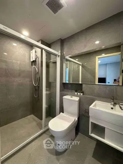 Modern bathroom with sleek shower, toilet, and vanity in a contemporary apartment.