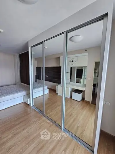 Modern bedroom with mirrored sliding closet doors and wooden flooring