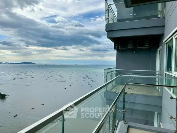 Stunning ocean view from modern apartment balcony with glass railing.