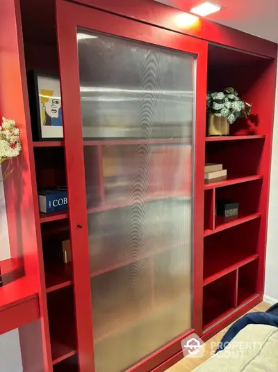 Modern red storage unit with sliding door and decorative shelves in stylish interior