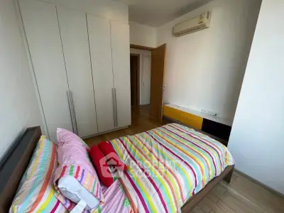 Cozy bedroom with colorful striped bedding and modern wardrobe, featuring air conditioning for comfort.