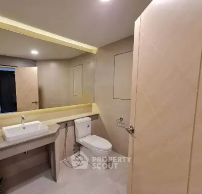 Modern bathroom with sleek fixtures and large mirror in a contemporary apartment.
