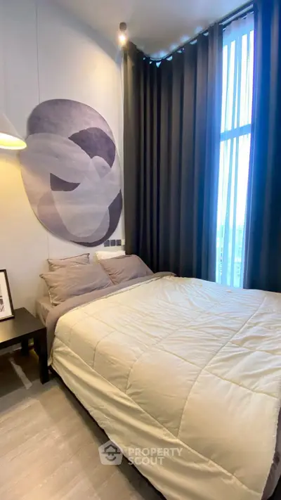 Modern bedroom with stylish decor and large window offering natural light.