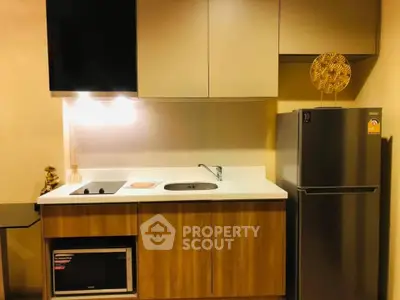 Modern kitchen with sleek cabinetry, built-in microwave, and stainless steel fridge.