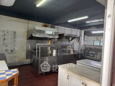 Spacious commercial kitchen with stainless steel appliances and ample workspace.