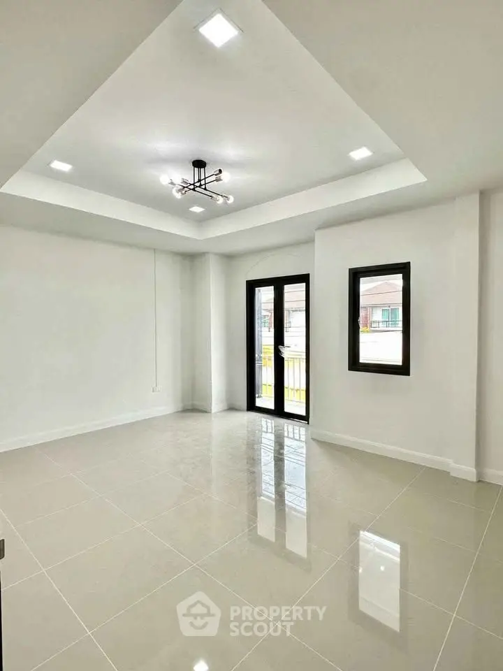 Spacious modern living room with large windows and glossy tiled floors.