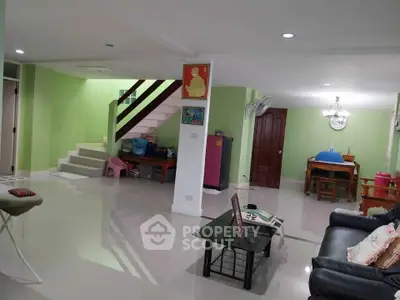 Spacious living room with modern decor and open layout, featuring a staircase and dining area.