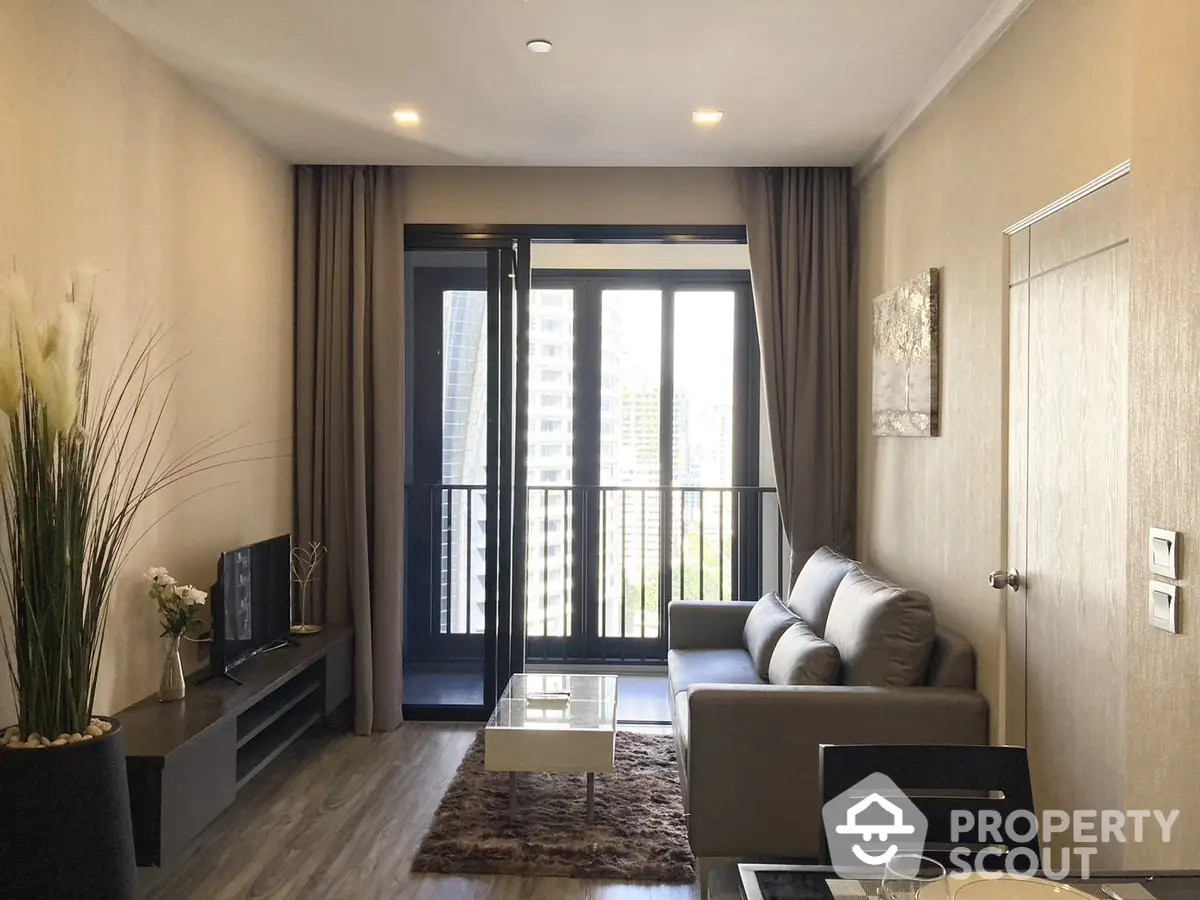 Elegant living room with plush seating, modern entertainment unit, and floor-to-ceiling windows leading to a sunny balcony.