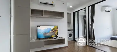 Modern living room with TV, air conditioning, and washing machine in sleek apartment.