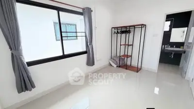 Spacious bedroom with large window and open closet, adjacent to modern bathroom.