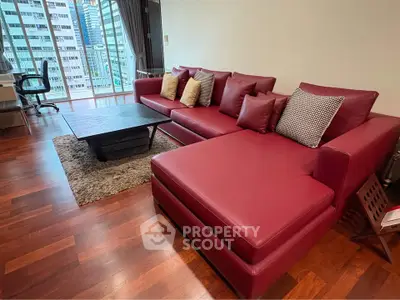Spacious living room with red leather sofa and city view, perfect for modern urban living.