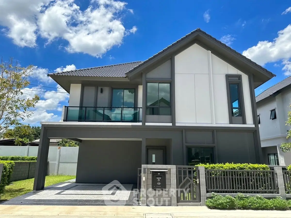 Modern two-story house with sleek design and spacious driveway under clear blue sky.