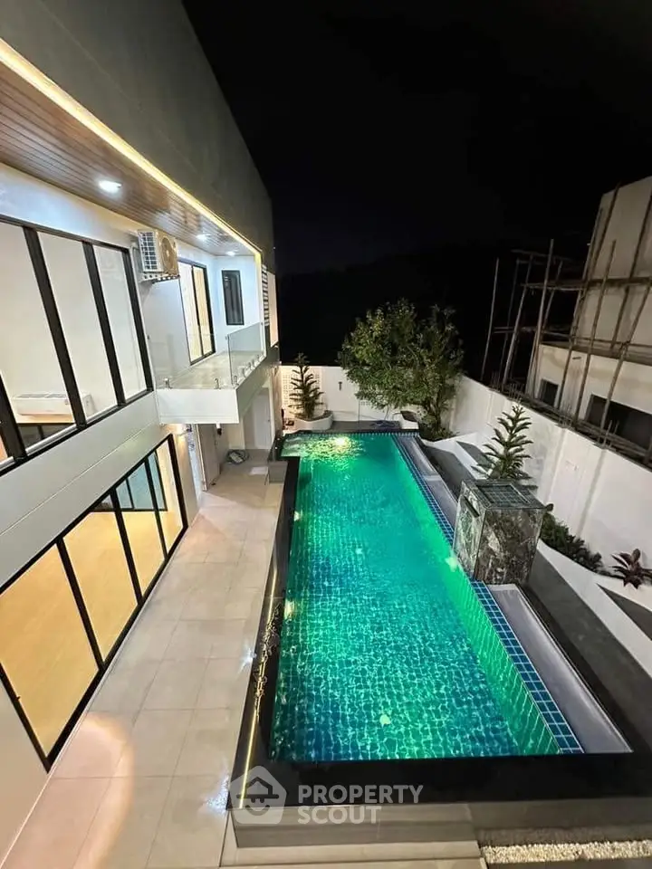 Luxurious modern home with stunning illuminated pool and elegant architecture at night.