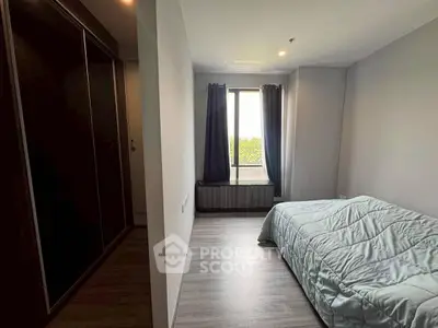 Cozy bedroom with large window and modern wardrobe, perfect for relaxation.