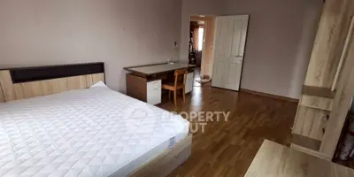 Spacious bedroom with wooden flooring and modern furniture, ideal for comfort and relaxation.