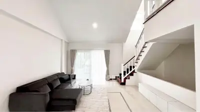 Spacious modern living room with sleek black sofa and elegant staircase