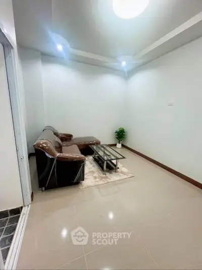 Cozy living room with modern sofa and glass coffee table, perfect for relaxation.
