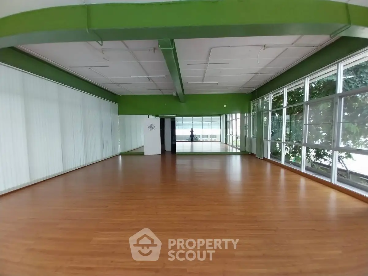 Spacious open room with large windows and wooden flooring, ideal for versatile use.