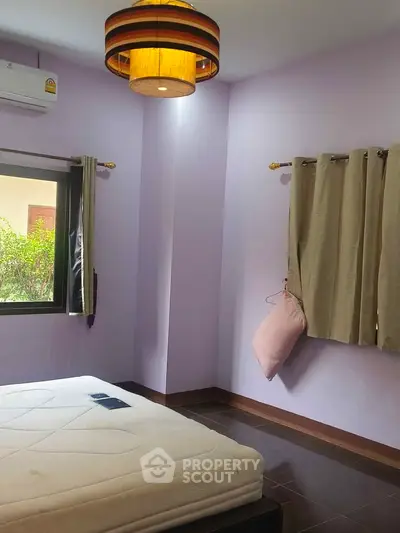Cozy bedroom with soft purple walls, large window, and stylish ceiling light fixture.