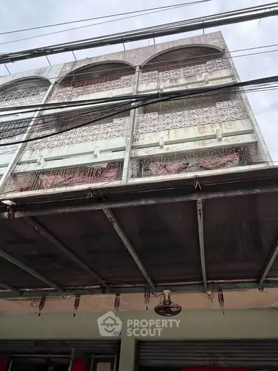 Charming multi-story building with intricate balcony railings and covered entrance, ideal for urban living.