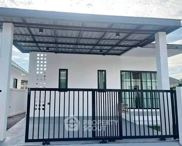 Modern minimalist house exterior with sleek metal gate and covered carport.