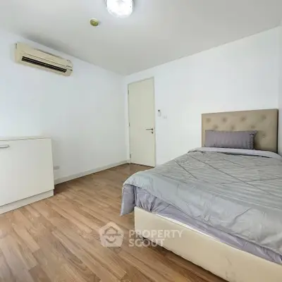 Modern bedroom with wooden flooring and air conditioning in a minimalist style apartment.