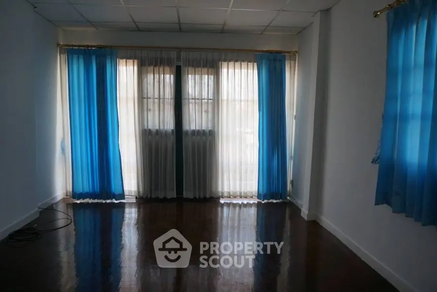 Spacious empty room with blue curtains and polished wooden floor
