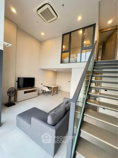 Modern loft apartment with stylish living room and mezzanine bedroom, featuring sleek staircase and contemporary decor.