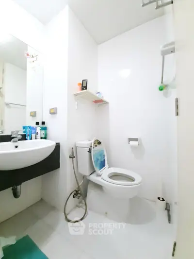 Modern bathroom with white tiles and essential fixtures in a compact space