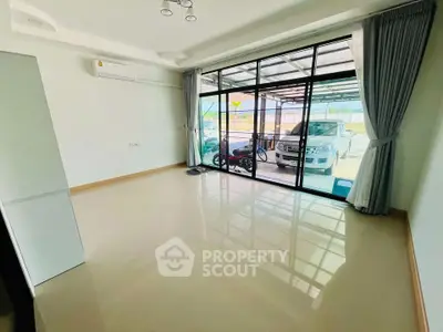 Spacious living room with large glass doors leading to a covered parking area, perfect for modern living.