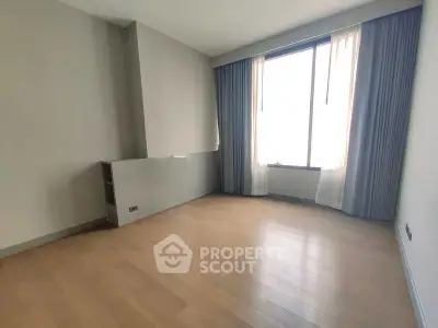 Spacious empty room with large window and wooden flooring, perfect for customization.
