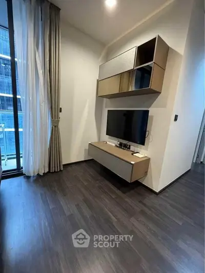 Modern living room with sleek TV setup and elegant floor-to-ceiling curtains.