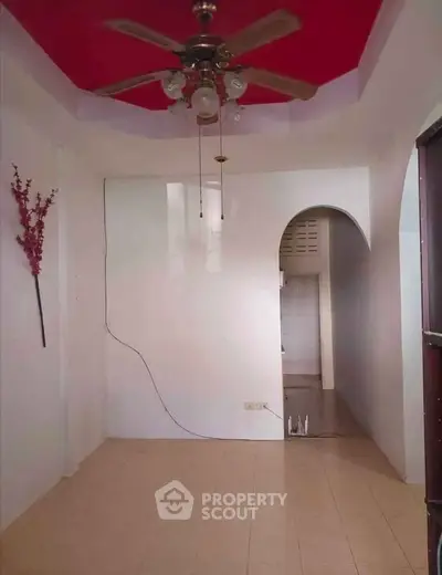 Spacious interior with ceiling fan and archway leading to kitchen area