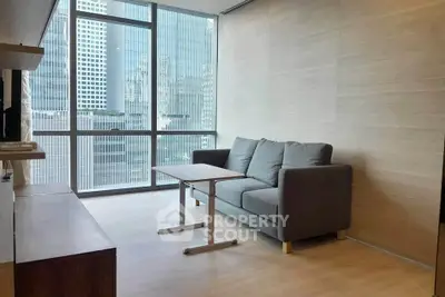 Modern living room with large windows and city view, featuring a cozy gray sofa and wooden accents.