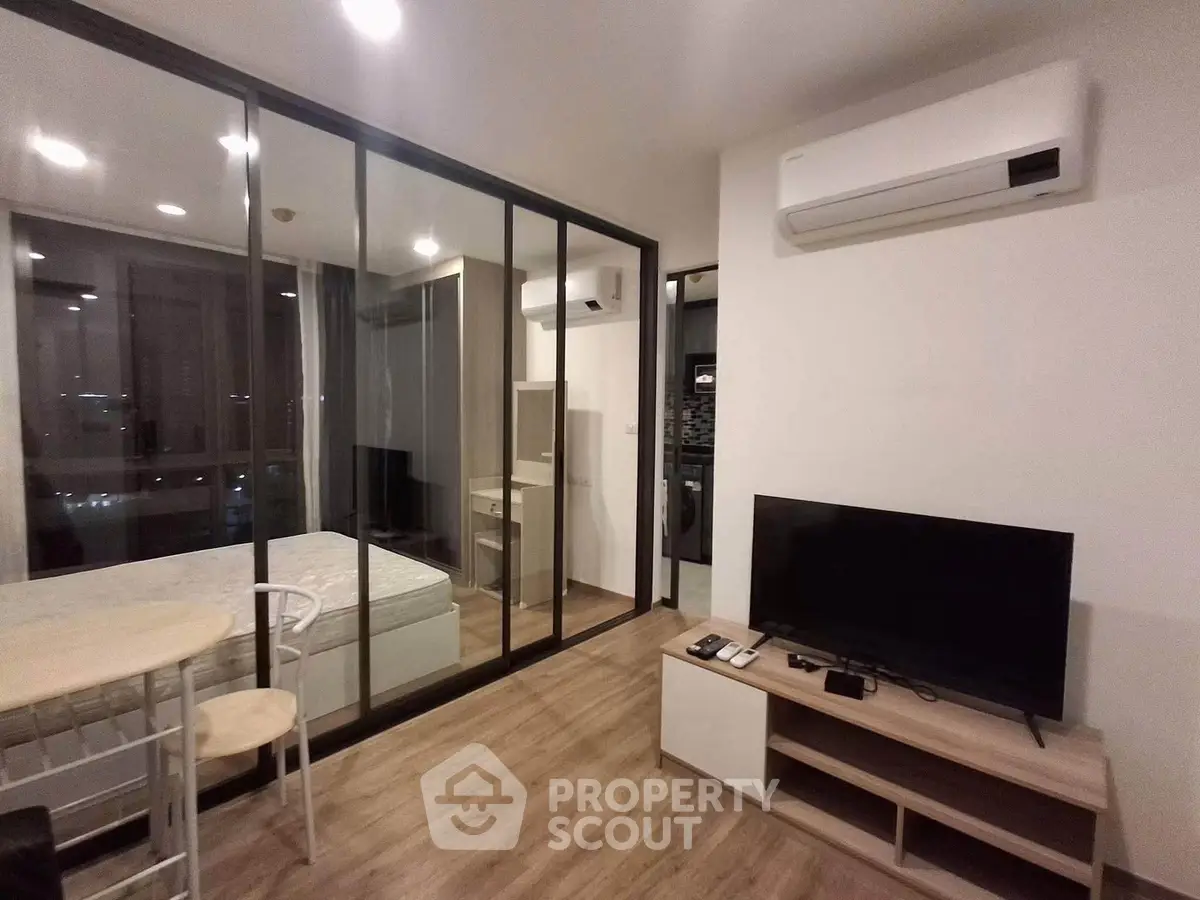 Modern studio apartment with glass partition, air conditioning, and sleek furnishings.
