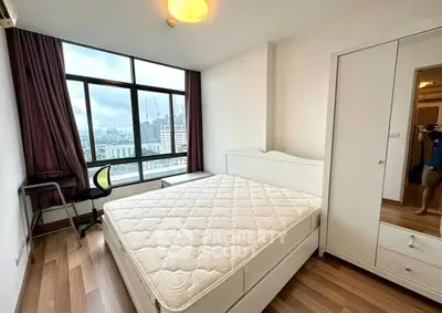 Spacious bedroom with large window offering stunning city views and modern furnishings.