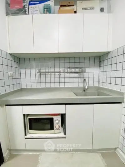 Compact kitchen with modern white cabinets and built-in microwave