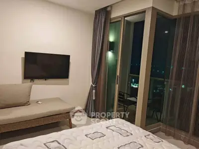 Modern bedroom with balcony view, featuring a wall-mounted TV and stylish decor.
