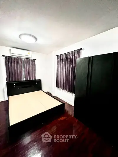 Spacious bedroom with wooden flooring and modern furnishings