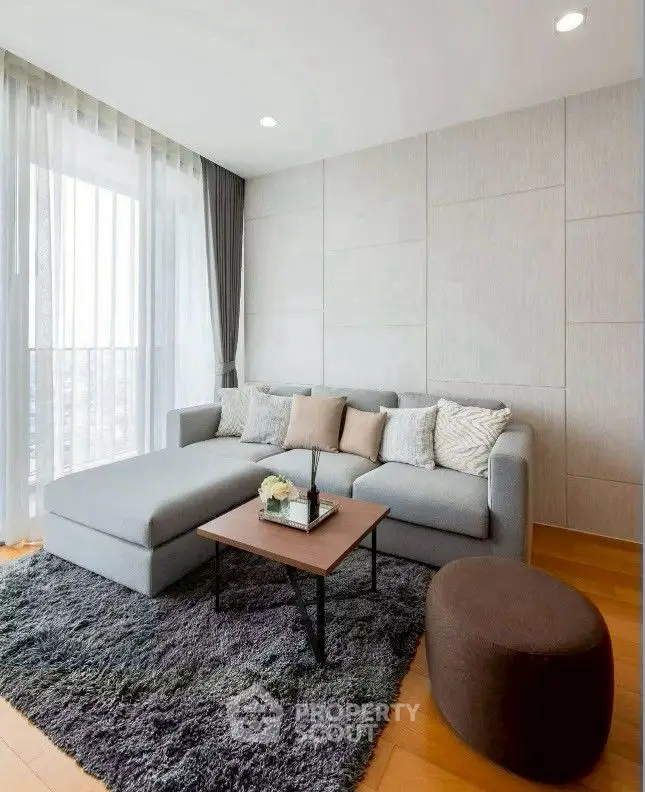 Modern living room with stylish gray sofa and floor-to-ceiling windows offering natural light.
