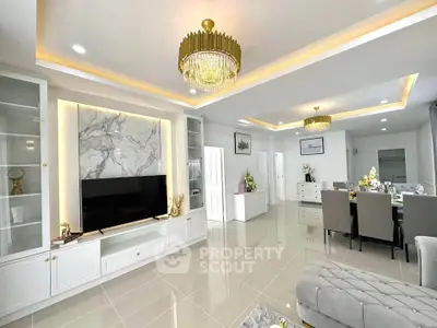 Luxurious living room with elegant chandelier and marble TV wall in open layout.
