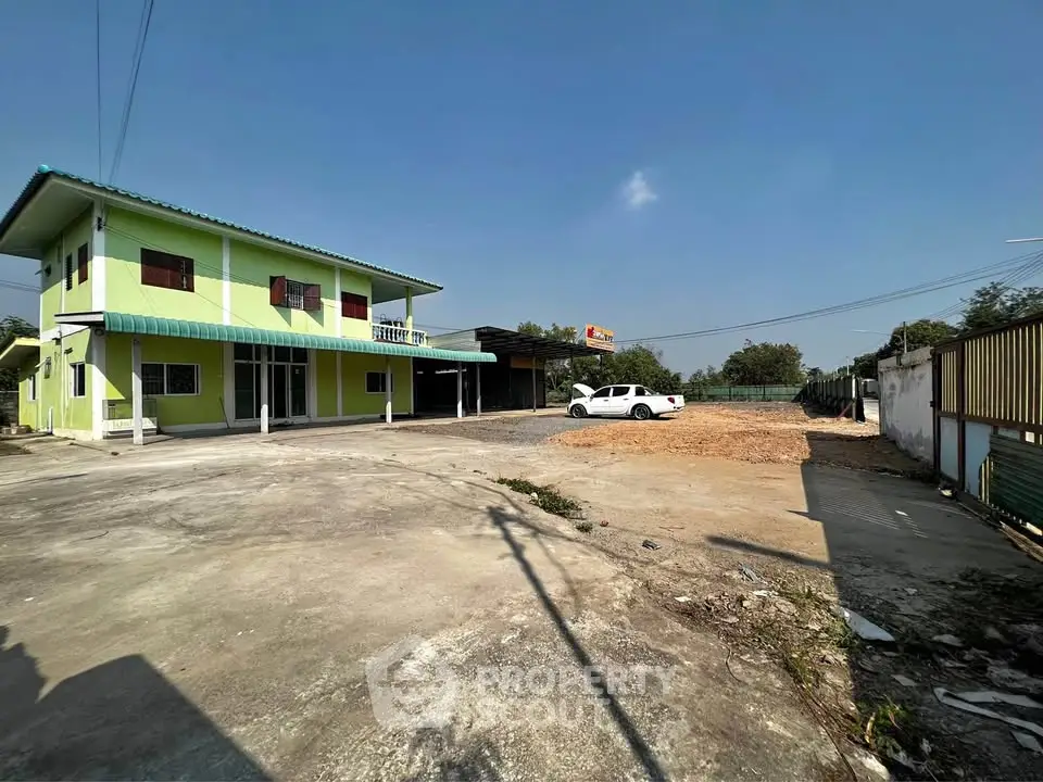 Spacious two-story green building with ample parking space and clear blue sky.
